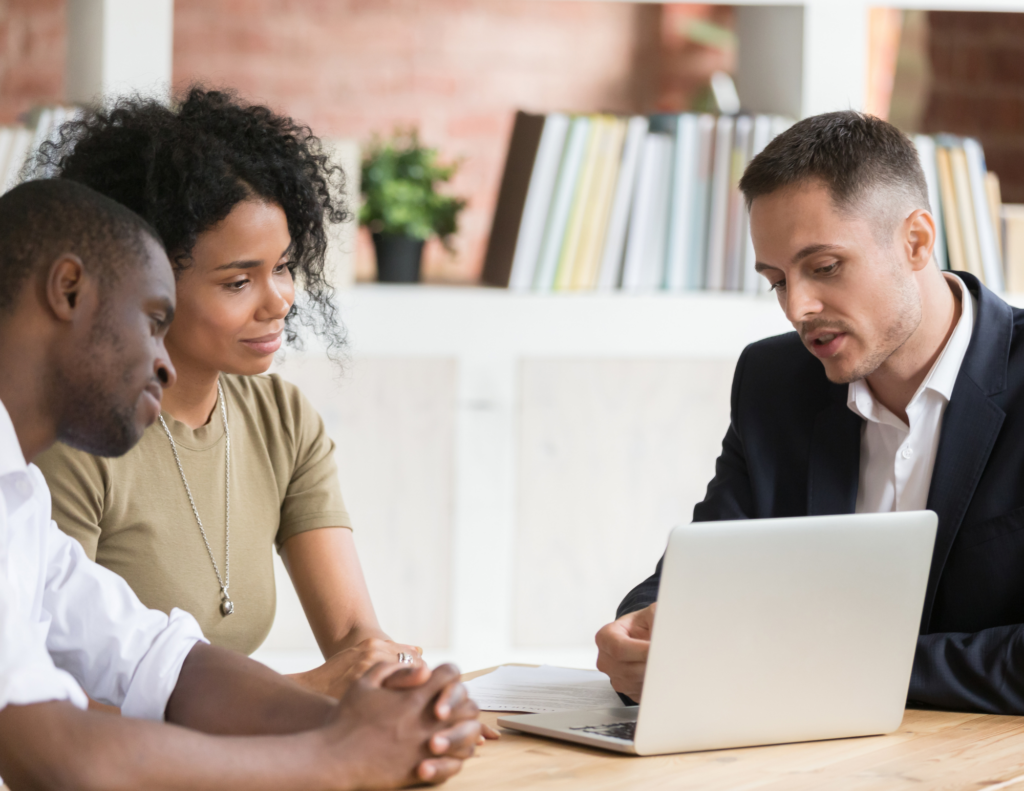 real estate agent presenting on laptop to couple