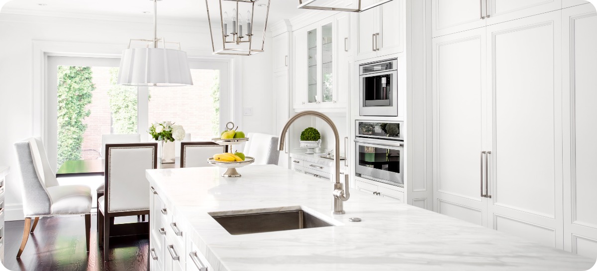 Photo of a kitchen with an island, a wall of cabinets, and an eating area.