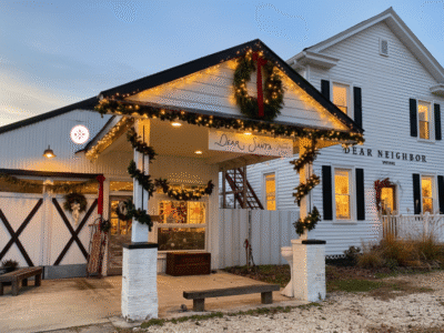 Two shops in old white wood buildings with black shutters and Christmas decorations