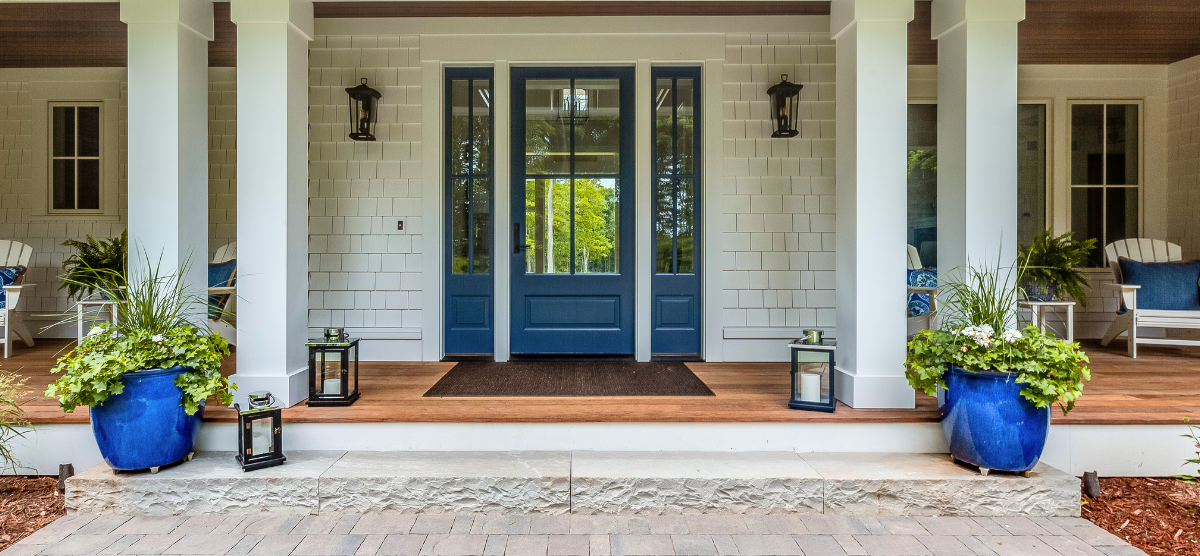 Front porch of a house showing a blue front door flanked by white columns.