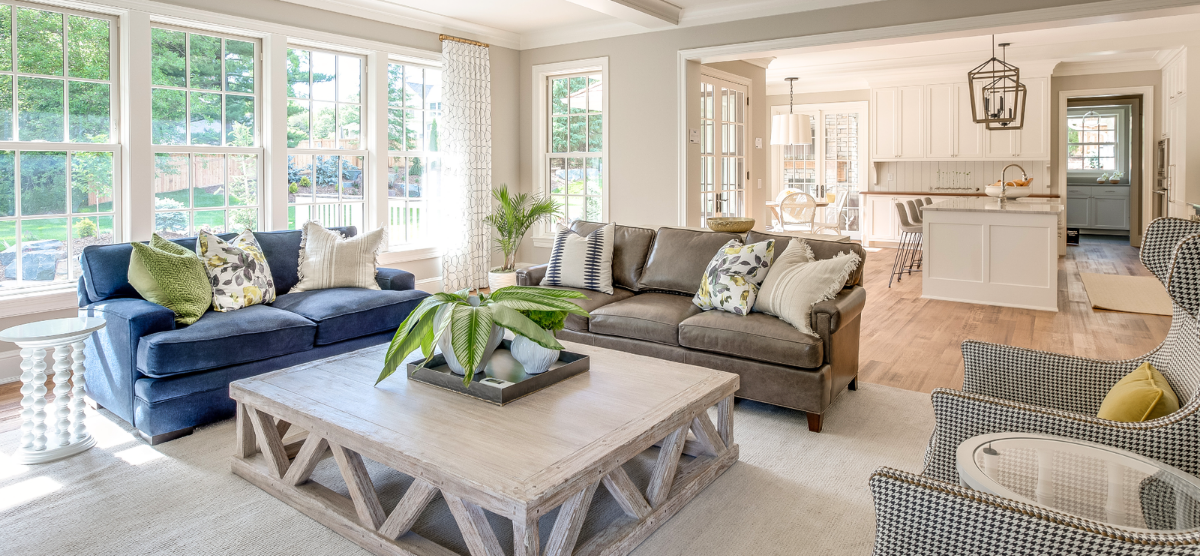 Sunroom with two sofas looking into a kitchen with white cabinets