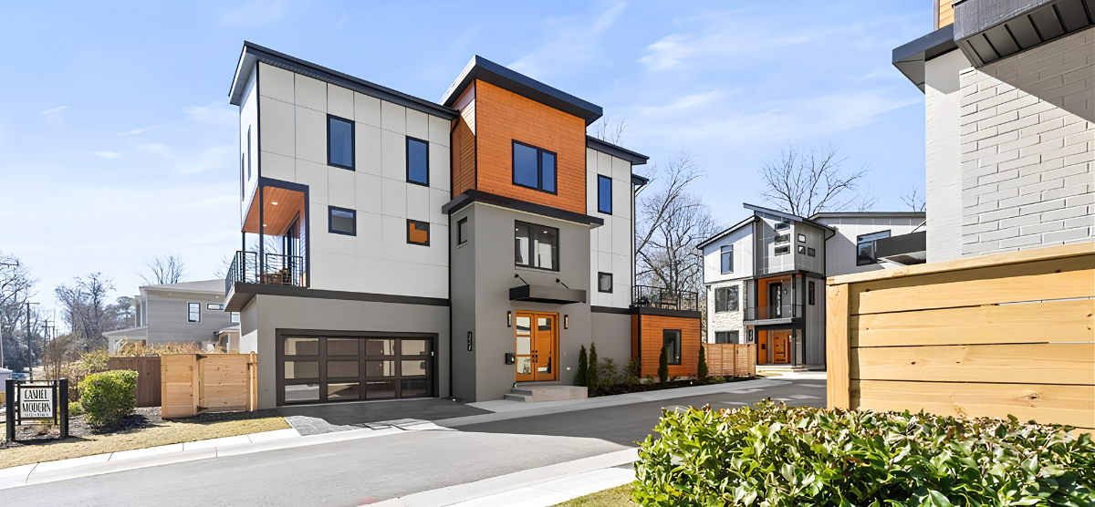 Modern home with a white, gray, and wood exterior. It's three levels with a garage.